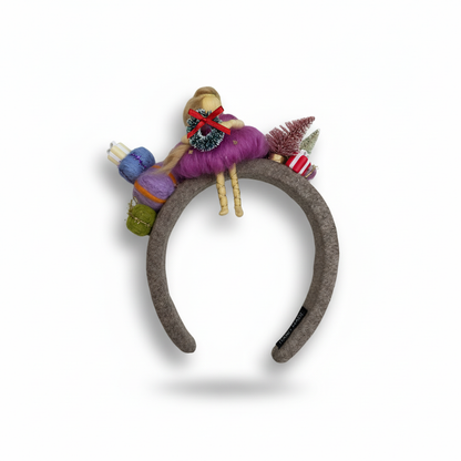 Decorative headband with colorful yarn and small figurines on a white background