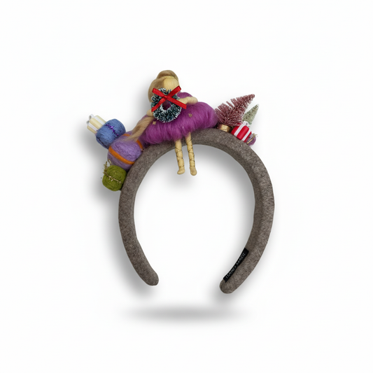 Decorative headband with colorful yarn and small figurines on a white background