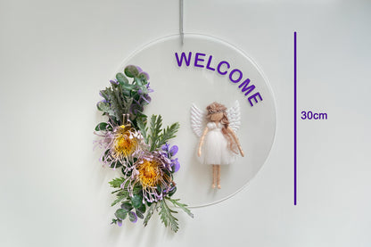 Decorative wall hanging with flowers, angel figure, and 'WELCOME' text on a white background.