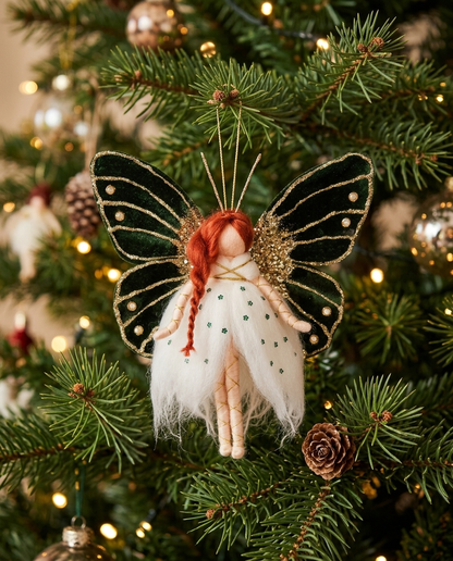 Emerald Butterfly Fairy hanging ornament (21 cm tall, 20 cm wide) suspended from a lush Christmas tree branch surrounded by warm festive fairy lights and holiday foliage
